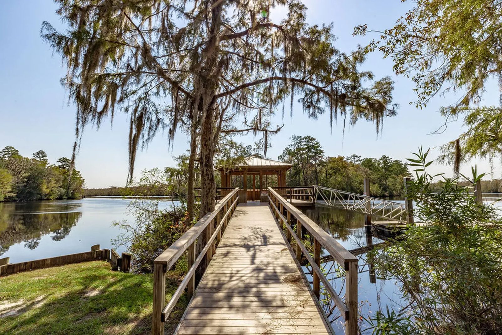 Wooden pier and covered gazebo over the St. Marys River at NorthShore, framed by live oaks and Spanish moss