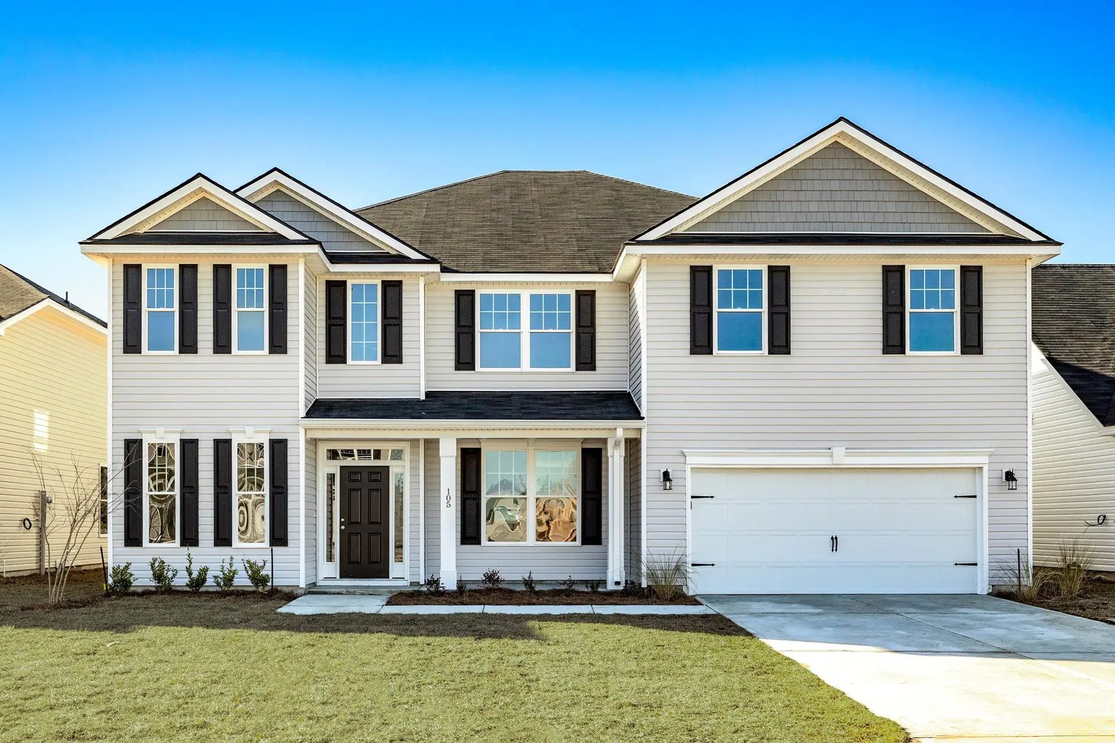 Two-story new-construction Smith Family Homes house at Settlers Hammock with light gray siding, a covered front entry, and a two-car garage