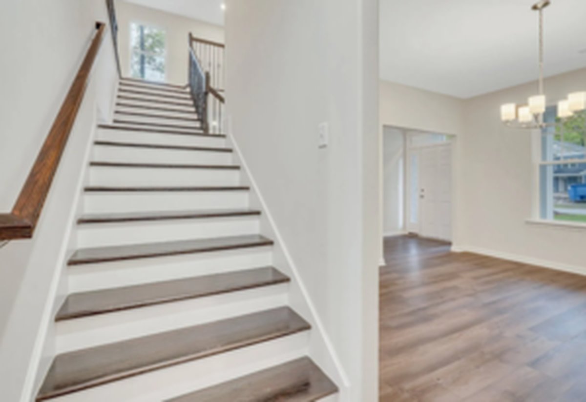 Interior view of the Gwinnett Plan foyer showing the staircase and adjoining living area with continuous LVP flooring
