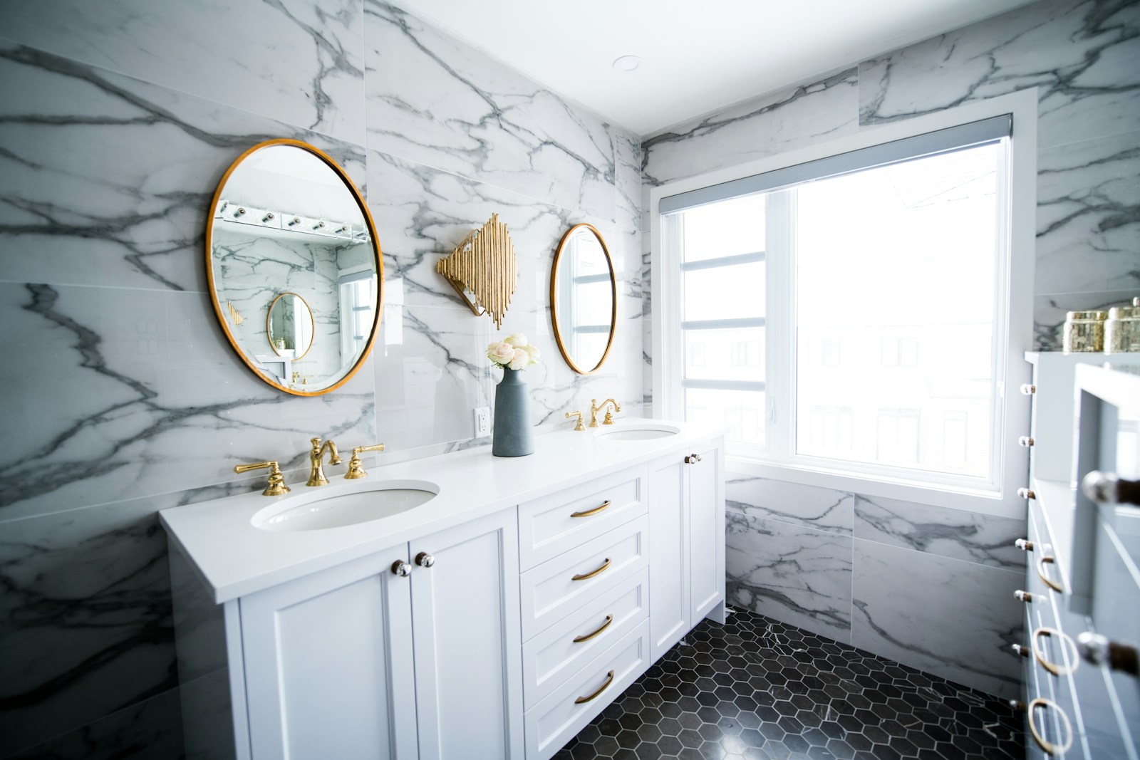 Primary bathroom with a double-sink vanity, granite countertop and a soaking tub beneath a window