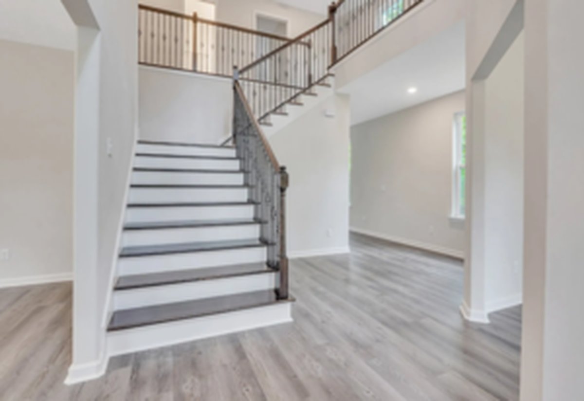 Two-story open foyer with a stylish staircase, wood treads and black metal railing, viewed from the entry
